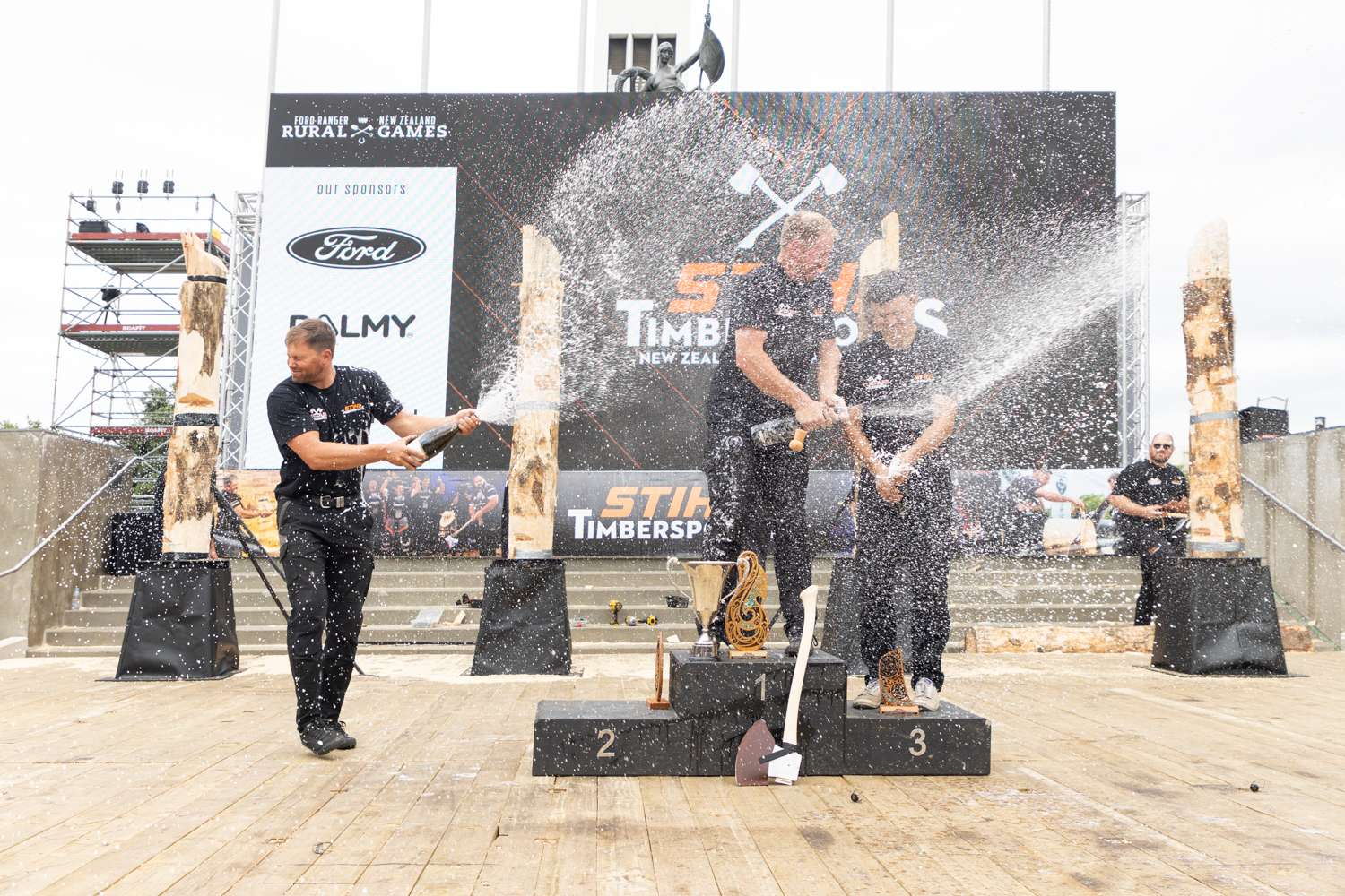 Timbersports winners podium unloading three bottles off champaign